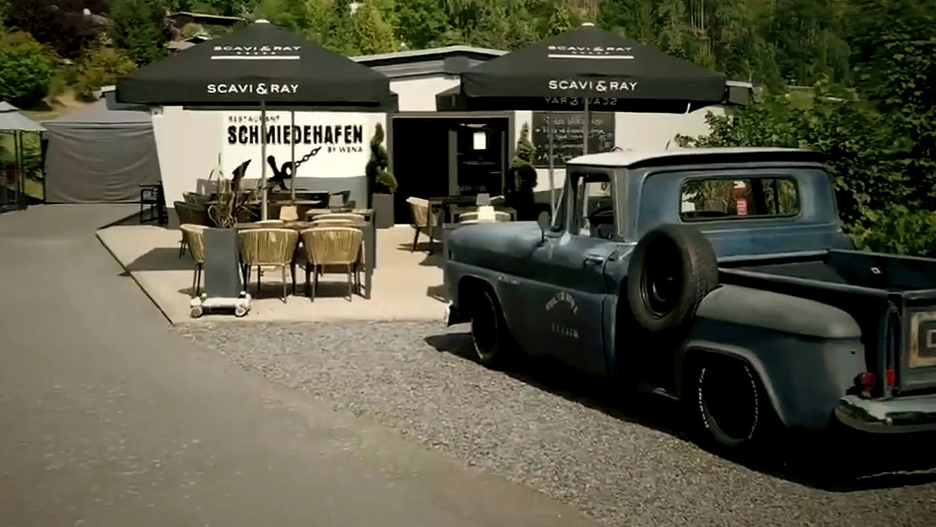 Der Schmiedehafen mit Terrasse, Schild und dem blauen Chevrolet